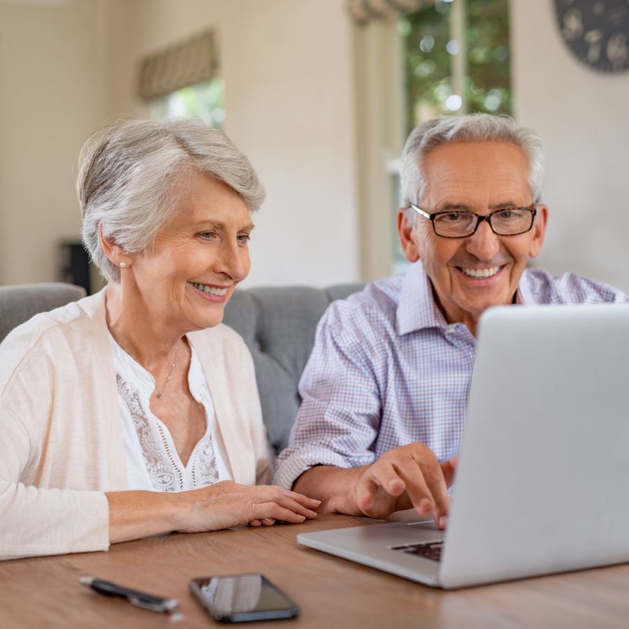 A couple in their seventies answering questions together on a laptop at home